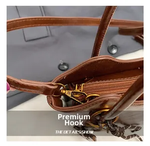 Detalle de los ganchos metálicos dorados y anillas en D en el bolso tipo cubo marrón