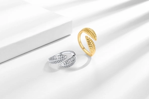 Dettaglio di anelli regolabili a forma di foglia in oro e argento con venature incise