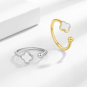 Elegant four-leaf clover open rings in gold and silver finish on white geometric display