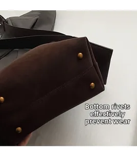 Detail view of the brown suede bucket bag base featuring four protective bronze rivets