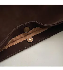 Detail of dark brown matte leather bucket bag showing bronze magnetic clasp and stitching