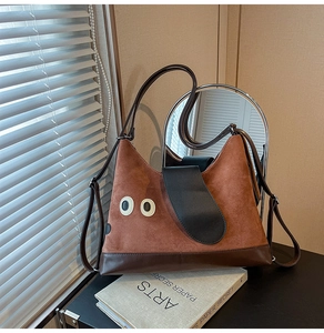 Dettaglio della borsa tote in pelle scamosciata marrone con orecchie creative su libri d'arte