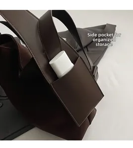 Detail view of the side pocket on a brown leather bucket bag for small items storage