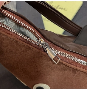 Dettaglio della cerniera in metallo argento e fodera a onde su una borsa tote in pelle scamosciata