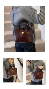 Détail d'un sac cabas bordeaux avec boucle dorée et foulard à pois sur fond épuré