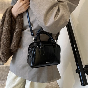 Minimalist black shiny bowling bag for women with dual handles and silver hardware