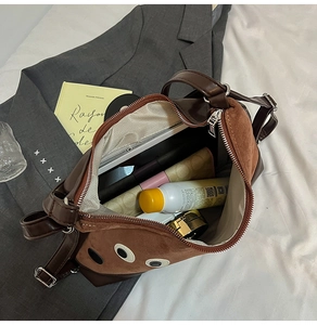 Dettaglio dell'interno capiente della borsa tote marrone con oggetti di uso quotidiano