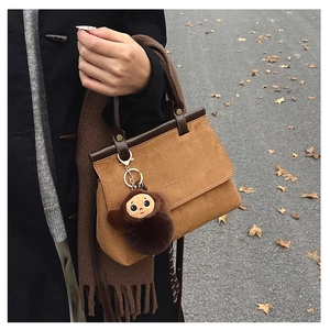 Gros plan du sac à main en daim marron avec pendentif singe et écharpe à franges