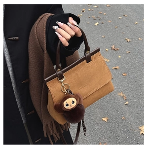 Détail du sac à main en daim marron avec pendentif singe en peluche en automne