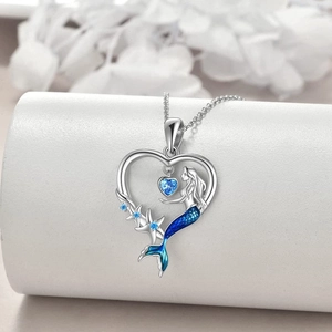 Silver mermaid heart necklace with blue gemstone and starfish pendant on white pedestal
