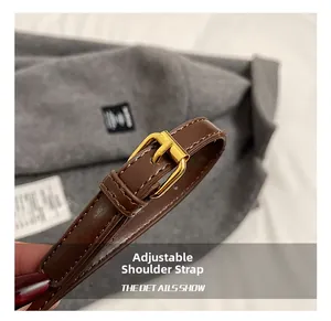 Détail de la bandoulière réglable en cuir marron foncé avec boucle en métal doré et couture