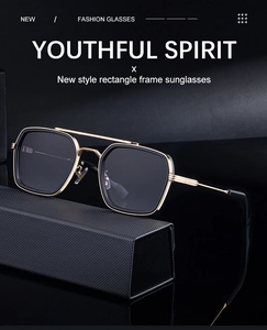 Close-up of golden rectangle sunglasses with double bridge on a textured black case