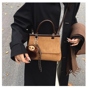 Détail d'un sac à main rétro en daim marron avec breloque singe et anse en cuir