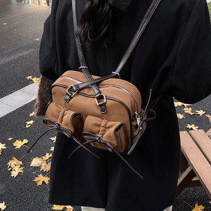 Vintage brown nylon shoulder bag with bow drawstring pockets on an autumn street