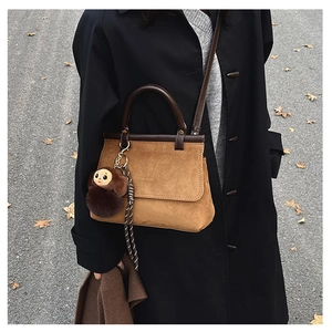 Sac à main en daim marron avec poignée en cuir foncé et pendentif singe en peluche