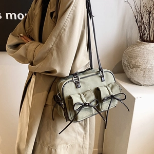 Olive green vintage shoulder bag with bow details and twin pockets on beige coat