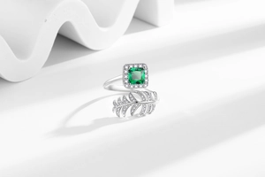 Detail of leaf ring featuring square green gemstone and white zircon in silver finish