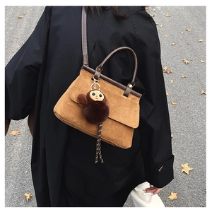 Détail d'un sac en daim caramel avec bandoulière en cuir et un joli pendentif singe