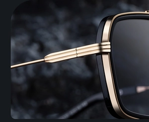 Close-up of golden metal hinges and black frame detail on luxury square sunglasses
