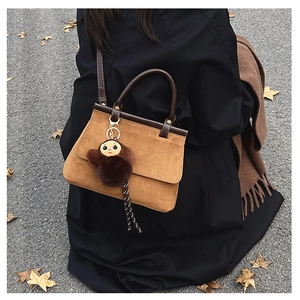 Sac bandoulière en daim marron avec poignée en cuir et charm singe en peluche, style automne