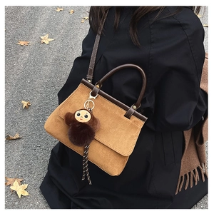 Détail du sac en daim marron avec pendentif singe en peluche et poignée rétro chic
