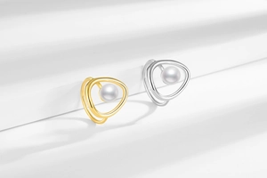 Artistic geometric rings with white pearls on a minimalist white textured backdrop