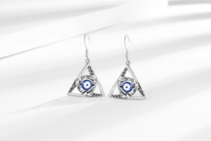 Detail of silver Evil Eye earrings with protective hand relief and Celtic knots