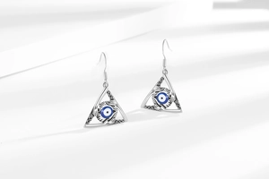 Detailed view of vintage Evil Eye earrings with blue eye and hand palm design on white cloth