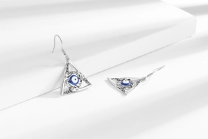 Detail view of triangular Evil Eye earrings with blue eye beads on a geometric stand