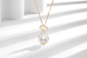 Macro detail of gold lucky bag pendant with micro-set zircons and freshwater pearl charm