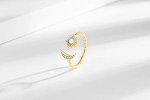 Detailed close-up of gold moon and sun ring with blue moonstone and pave crystals