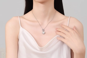 Detail of freshwater pearl pendant necklace with diamond bow on silk dress