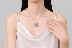 Detail of silver spider pendant necklace with punk style on model with pink silk top