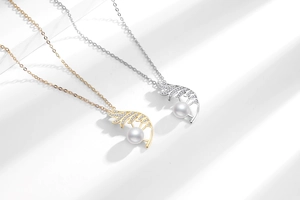 Macro detail of gold and silver feather pendant necklaces with inlaid stones and pearls