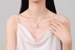 Close-up of elegant feather-shaped necklace with zircon pavé and white pearl pendant