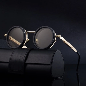 Detail of round punk sunglasses with gold metal bridge resting on a leather case