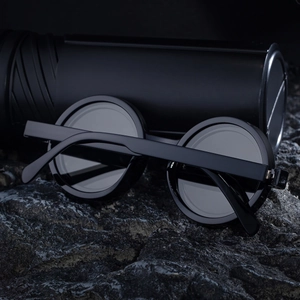 Detail of retro round matte black polarized sunglasses on textured black rock
