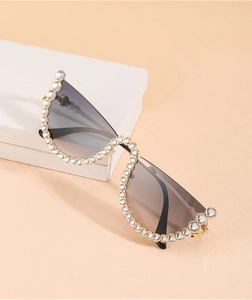 Détail de lunettes de soleil papillon sans monture avec strass et bordure dorée