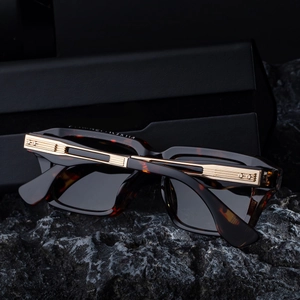 Detail of dark tortoiseshell sunglasses with golden metallic temples on black rock