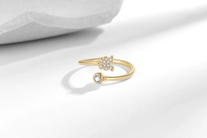 Detail of 18K gold butterfly ring with pave zircons and a round solitaire on white