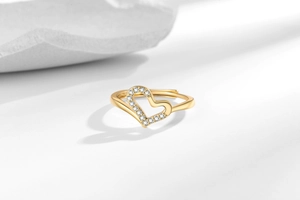 Detailed close-up of a gold heart ring featuring half-pave cubic zirconia on a white stone