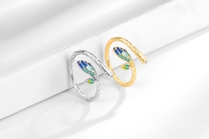 Detail of silver and gold leaf rings with blue-green enamel on textured branch bands