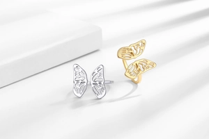 Detailed view of hollow butterfly wing rings in gold and silver finish with cutout texture