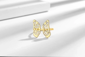 Detailed view of a gold hollow butterfly ring with 3D openwork on a white pedestal