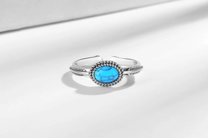 Detailed close-up of retro silver turquoise ring with feather carvings and rope edge
