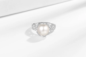 Macro shot of silver-tone hollow carved floral ring band with a large white pearl detail