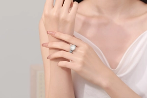 Detailed close-up of a large white pearl ring with vintage hollowed-out vine engravings