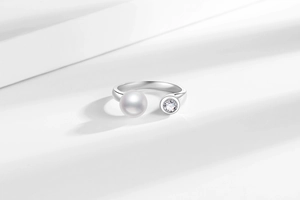 Detail of adjustable silver ring featuring a lustrous pearl and a sparkling zircon gem