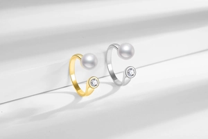 Close-up of adjustable gold and silver pearl rings with zircon stone on a white podium