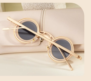 Close-up of golden dual-rim round sunglasses with metallic temples and leather case
